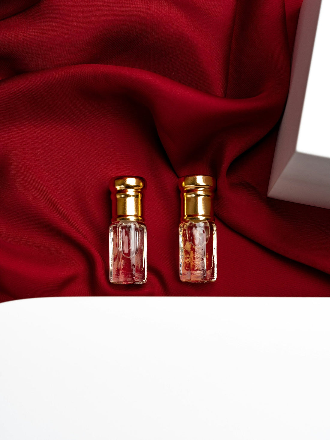 Two perfume bottles arranged on red fabric, representing a fragrance wardrobe and scent layering